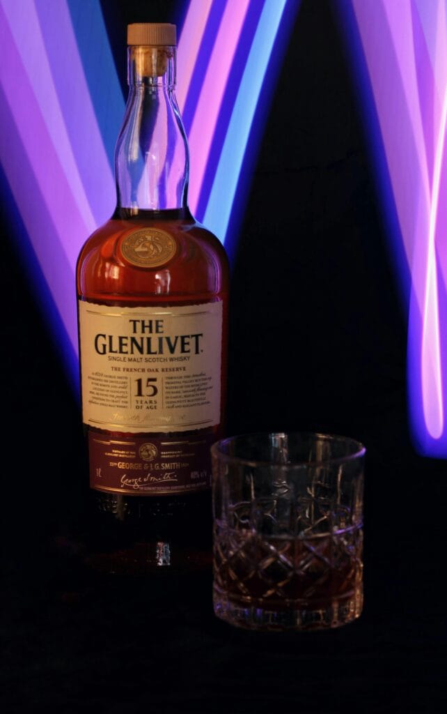 A bottle of The Glenlivet 15 Year Old Scotch whisky with colorful light trails in the background.