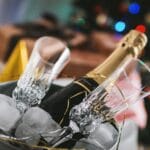 Close-up of champagne bottle and glasses in ice bucket, perfect for holiday festivities.